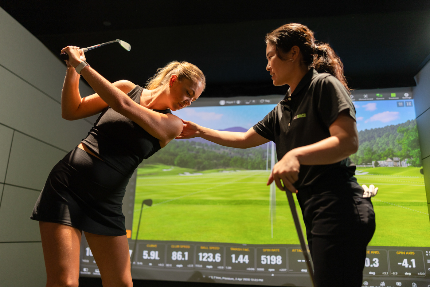 PGA coach guiding a member through her swing on the simulator